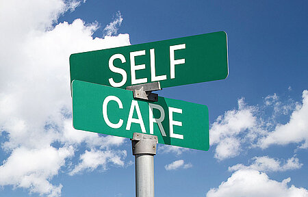 Zwei Schilder zeigen in unterschiedliche Richtungen mit den Aufschriften SELF und CARE